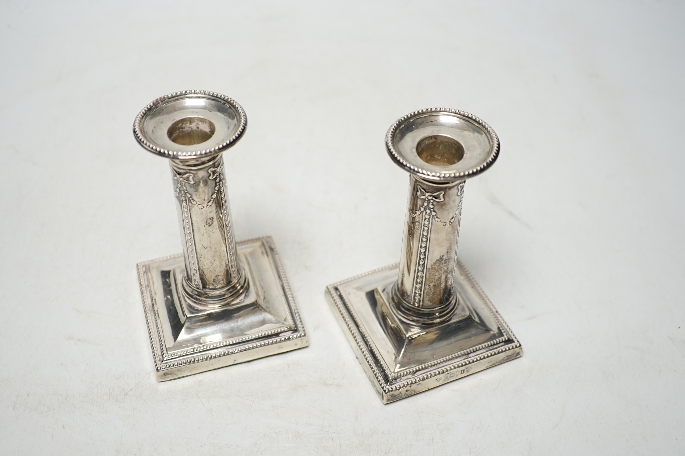 A pair of Edwardian silver dwarf candlesticks, by Goldsmiths & Silversmiths Co Ltd, London, 1904, 12.1cm, weighted. Condition - poor to fair